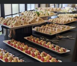 A buffet table with assorted sandwiches and skewered appetizers arranged on platters.